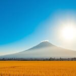 Ilustrasi AI langit cerah di atas sawah menguning dengan gunung di kejauhan