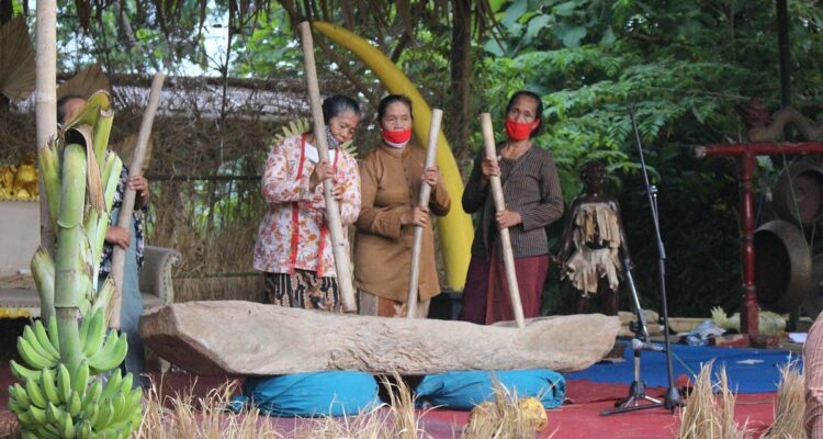 Warga memainkan kesenian gejog lesung dengan alu kayu